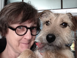 Susan McCully, a white woman wearing dark rimmed glasses, poses with her dog.