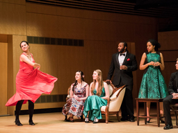 In colorful costumes, a group of actors perform on stage.