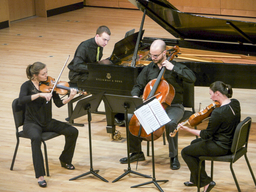 A group of four musicians performs on a concert stage.