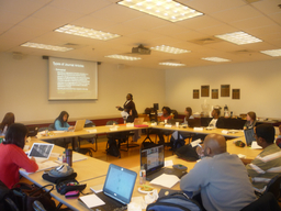 Picture of a previous cohort of Dissertation House, a group of 18 people seating on a conference room, with their laptops working