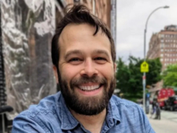 smiling man with beard on a city street