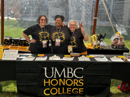 three Honors staff standing behind a banner that says UMBC Honors College