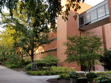 Math / Psych Building (brick building and glass skywalk) in the summer with lush green trees.