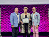 A person holding a certificate with two other persons on either side.