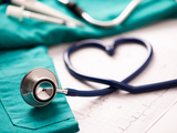 hospital scrubs in background with stethoscope in foreground coiled in the shape of a heart